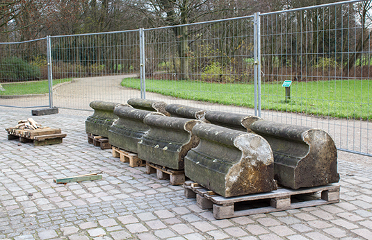 Natursteine der Brunneneinfassung werden auf Paletten gelagert.